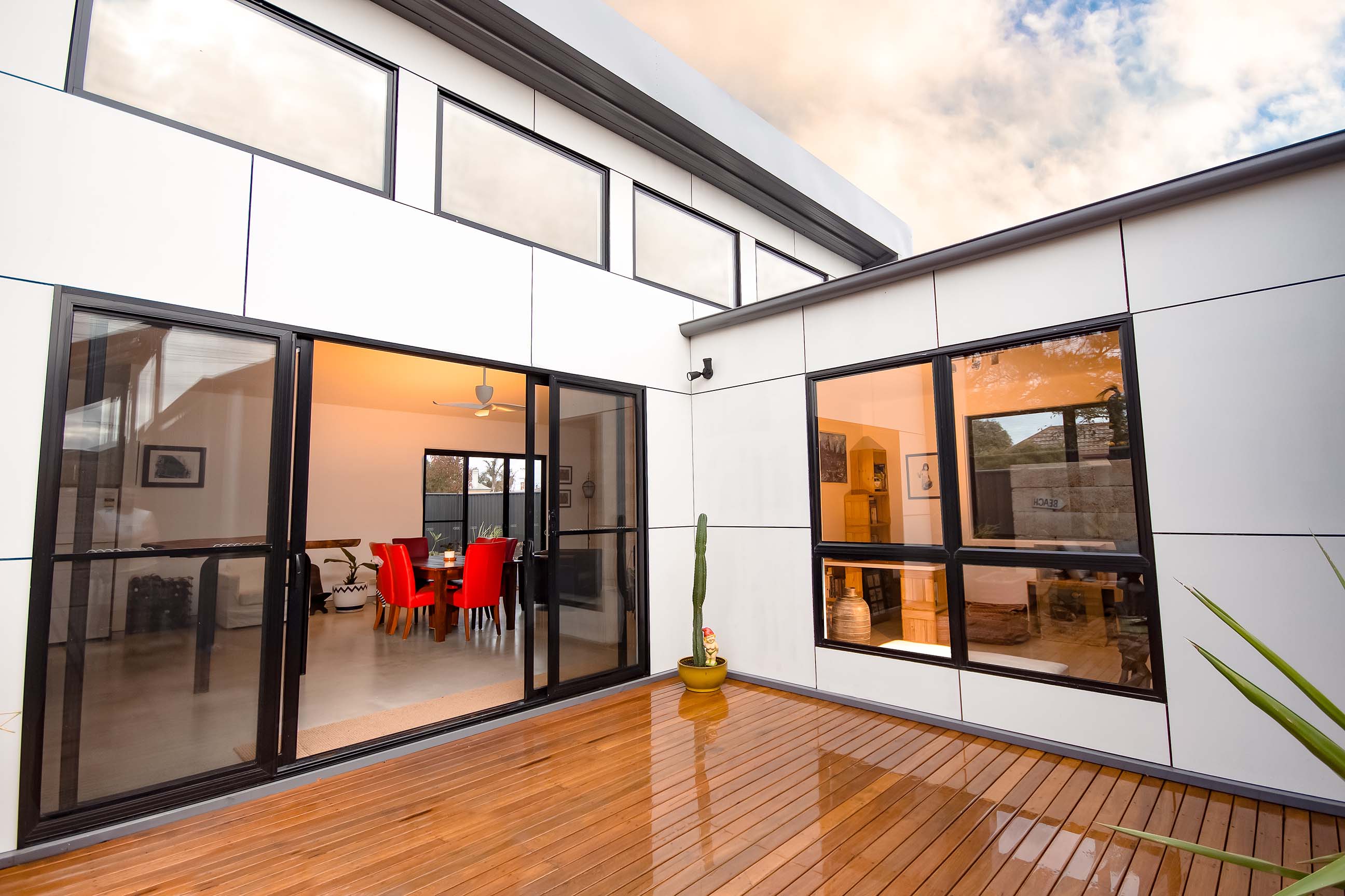 A view from the outdoor courtyard towards the house with a timber deck and large sliding glass doors